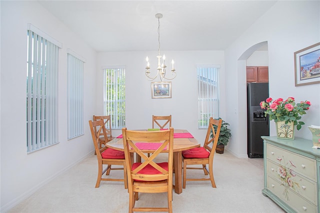 carpeted dining space with an inviting chandelier