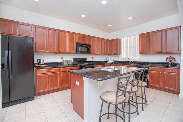 kitchen with light tile patterned floors, black appliances, a textured ceiling, and a kitchen island