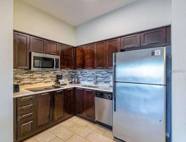 kitchen with dark brown cabinetry, light tile patterned floors, sink, stainless steel appliances, and decorative backsplash