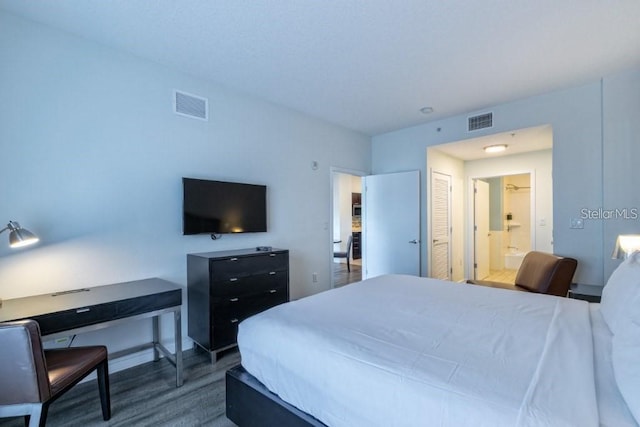 bedroom with a closet, connected bathroom, and dark wood-type flooring