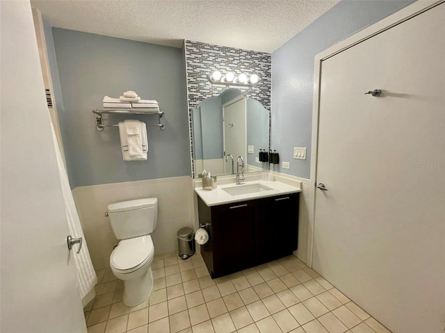 bathroom featuring vanity, tile walls, tile patterned floors, toilet, and a textured ceiling