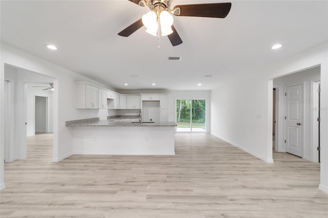 kitchen with sink, light hardwood / wood-style flooring, kitchen peninsula, and white cabinetry