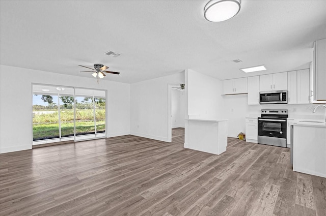 kitchen with light hardwood / wood-style floors, ceiling fan, sink, white cabinets, and appliances with stainless steel finishes