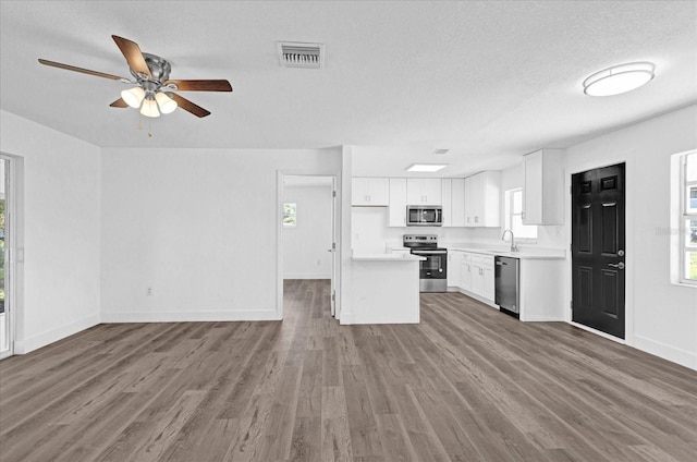 kitchen featuring wood-type flooring, stainless steel appliances, sink, and white cabinetry