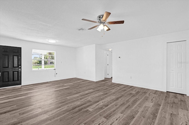 unfurnished living room featuring ceiling fan, a textured ceiling, and dark hardwood / wood-style flooring