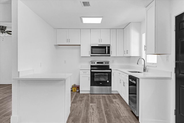 kitchen with ceiling fan, sink, wood-type flooring, white cabinetry, and stainless steel appliances