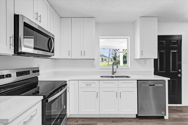 kitchen with white cabinetry, sink, dark hardwood / wood-style floors, appliances with stainless steel finishes, and a textured ceiling