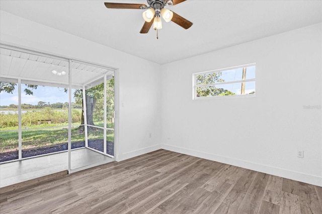 unfurnished room featuring ceiling fan, hardwood / wood-style flooring, and a healthy amount of sunlight