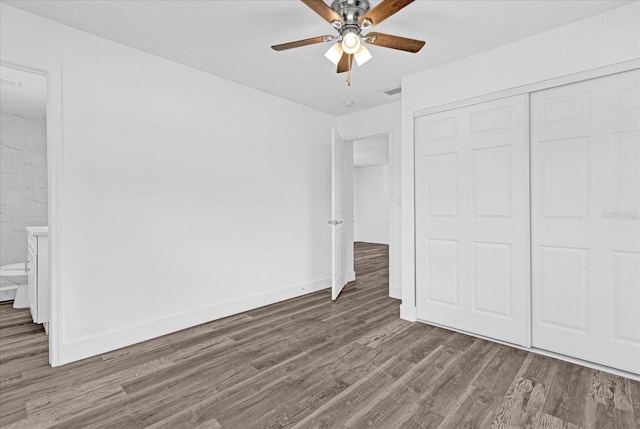 unfurnished bedroom with a closet, dark hardwood / wood-style floors, connected bathroom, and ceiling fan