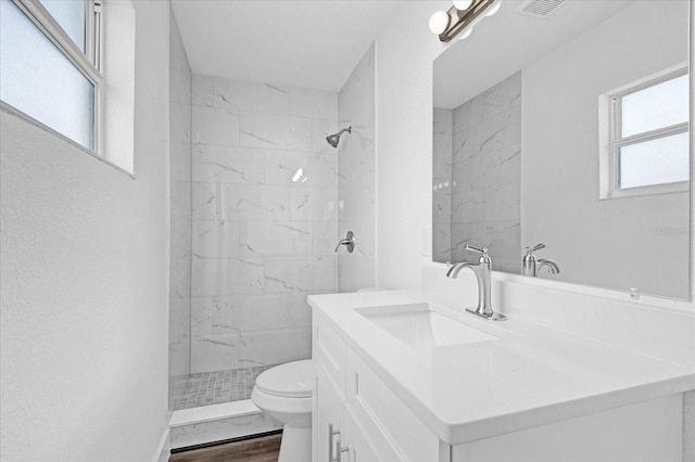 bathroom with wood-type flooring, vanity, toilet, and a healthy amount of sunlight