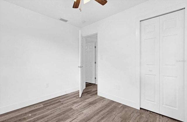 unfurnished bedroom with ceiling fan, a closet, and wood-type flooring