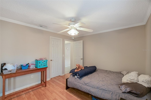 bedroom with ornamental molding, light hardwood / wood-style floors, a textured ceiling, and ceiling fan