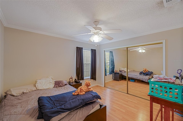 bedroom with ornamental molding, hardwood / wood-style floors, ceiling fan, and a closet