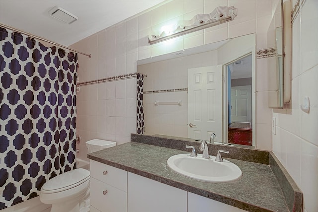 full bathroom with toilet, vanity, and tile walls