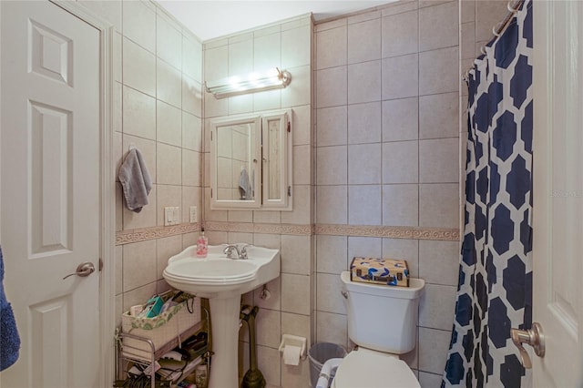 bathroom featuring toilet, tile walls, sink, and curtained shower