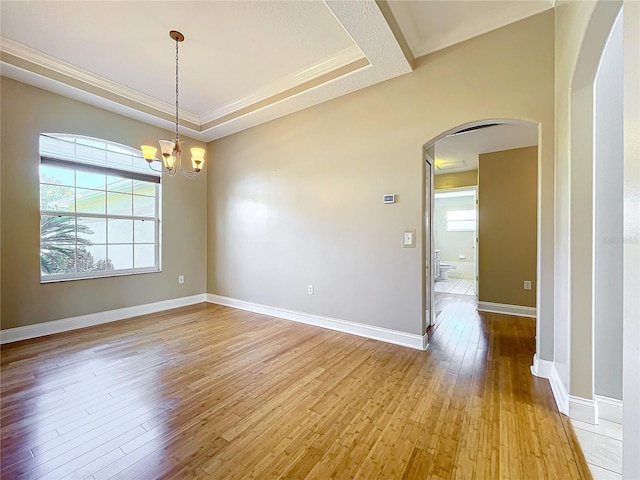 empty room featuring a wealth of natural light, light hardwood / wood-style flooring, and an inviting chandelier