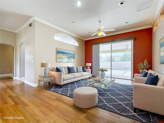 living room featuring ceiling fan, a textured ceiling, ornamental molding, and hardwood / wood-style floors