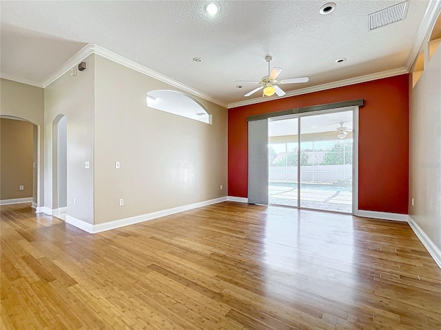 spare room featuring a textured ceiling, ornamental molding, and light wood-type flooring