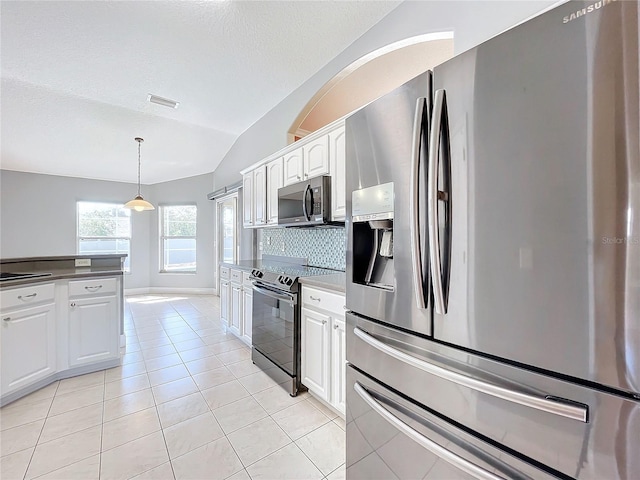 kitchen featuring light tile patterned floors, appliances with stainless steel finishes, white cabinetry, vaulted ceiling, and pendant lighting