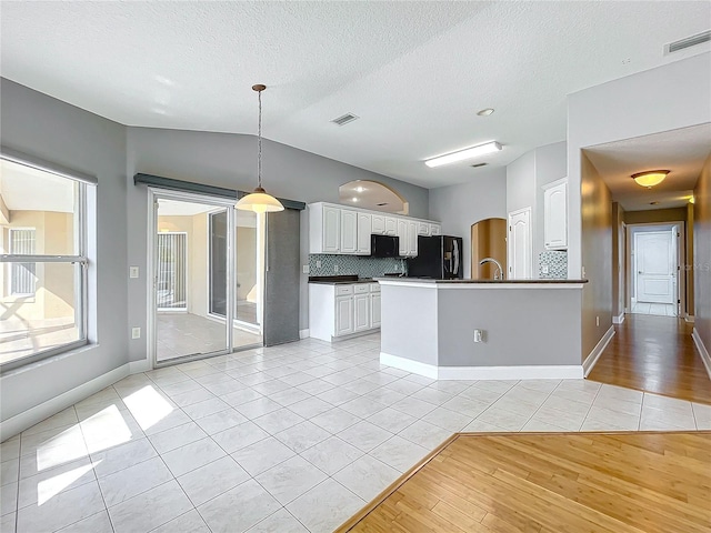 kitchen featuring vaulted ceiling, black appliances, light hardwood / wood-style flooring, and white cabinets