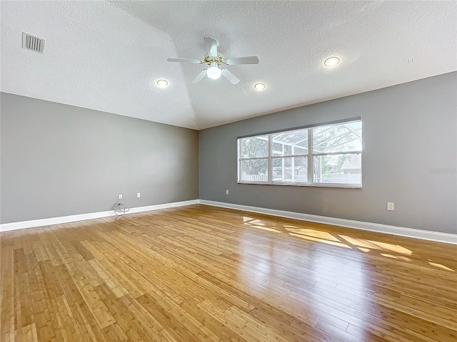 spare room with a textured ceiling, light wood-type flooring, and ceiling fan