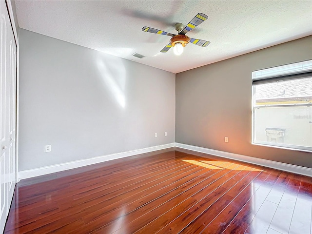 unfurnished room with ceiling fan, a textured ceiling, and dark hardwood / wood-style floors