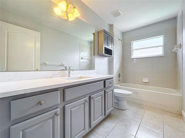 full bathroom with tiled shower / bath, a chandelier, toilet, vanity, and tile patterned flooring