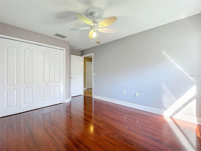 unfurnished bedroom featuring dark hardwood / wood-style flooring, a textured ceiling, a closet, and ceiling fan