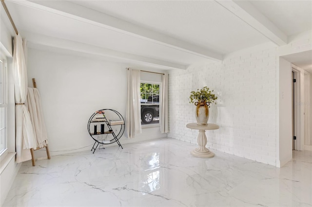 spare room featuring beamed ceiling and brick wall