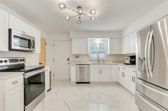 kitchen with white cabinetry, stainless steel appliances, sink, and an inviting chandelier