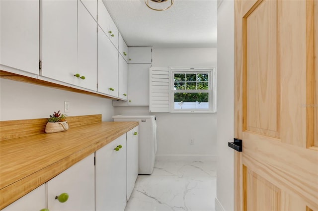 laundry room featuring washer / dryer, a textured ceiling, and cabinets