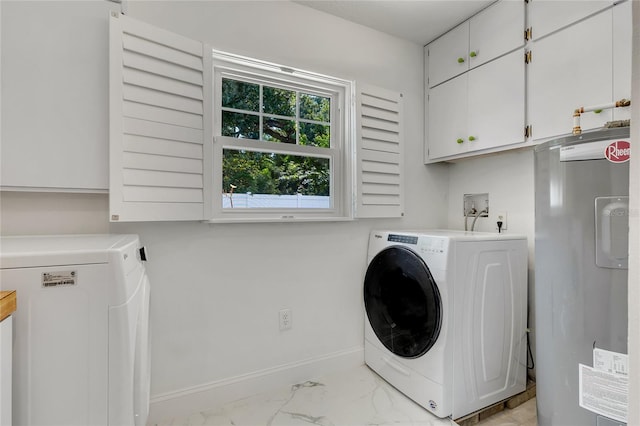 clothes washing area featuring cabinets, water heater, and separate washer and dryer