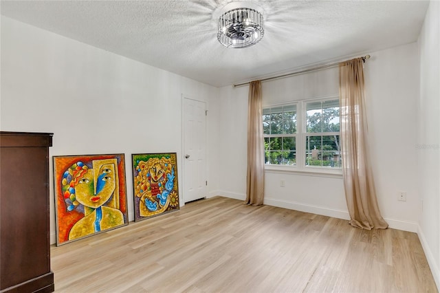 recreation room with a textured ceiling and light hardwood / wood-style floors