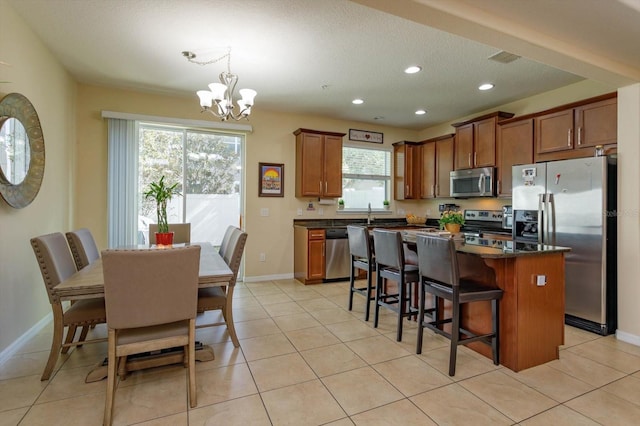 kitchen with a notable chandelier, stainless steel appliances, light tile patterned floors, and a kitchen island