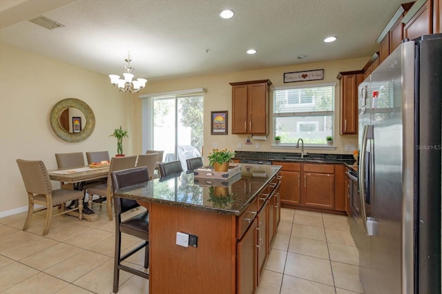 kitchen featuring a breakfast bar area, a center island, decorative light fixtures, light tile patterned floors, and stainless steel refrigerator