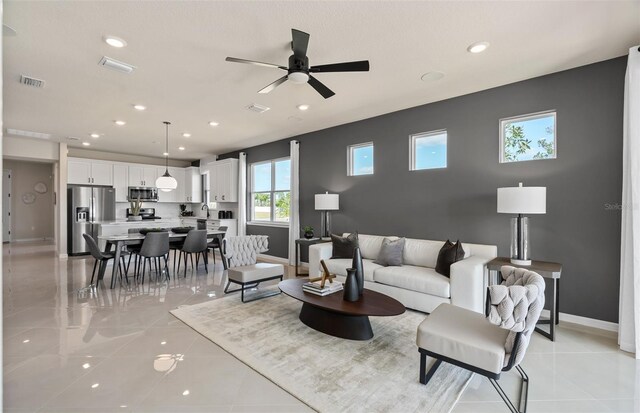 tiled living room with ceiling fan and sink