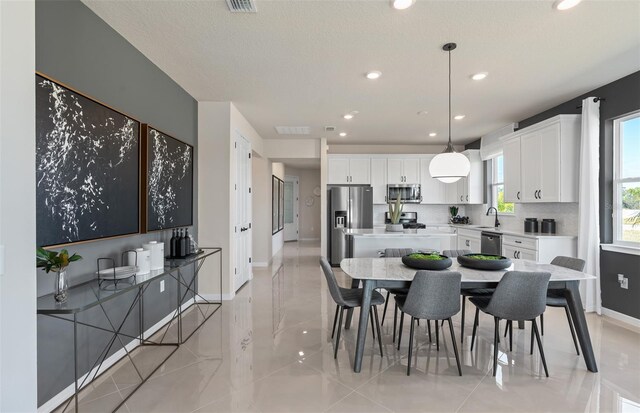 tiled dining space with sink and a textured ceiling