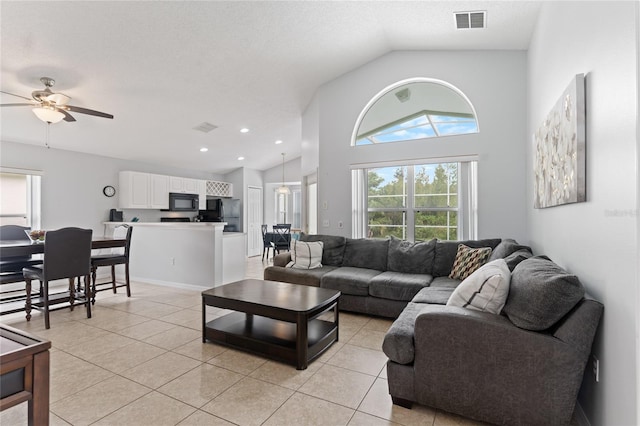 living room with ceiling fan, light tile patterned flooring, a textured ceiling, and high vaulted ceiling