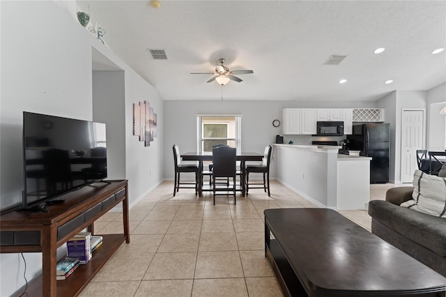 living room with light tile patterned flooring, ceiling fan, and a textured ceiling