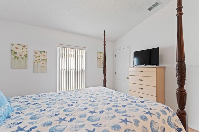 bedroom with a textured ceiling and vaulted ceiling