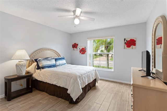 bedroom featuring light hardwood / wood-style flooring, a textured ceiling, and ceiling fan