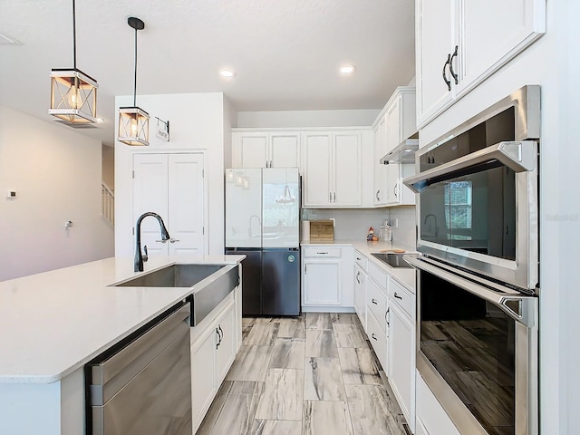 kitchen with appliances with stainless steel finishes, white cabinetry, pendant lighting, and sink