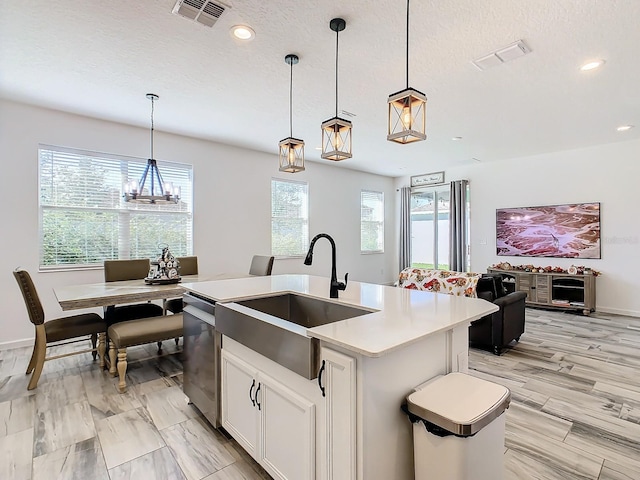 kitchen with white cabinets, a wealth of natural light, a kitchen island with sink, and hanging light fixtures