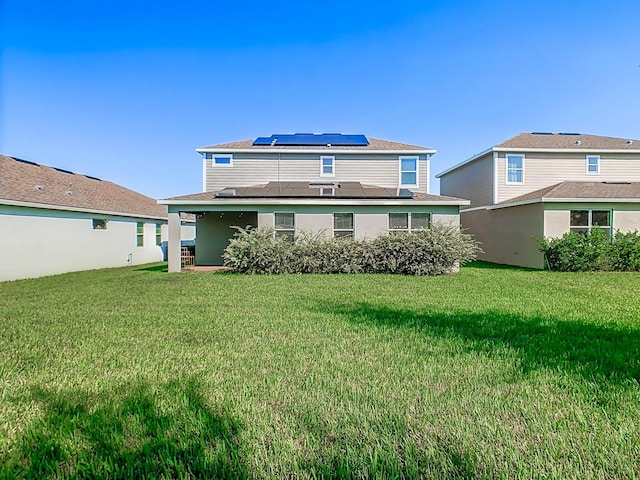 rear view of property with solar panels and a yard