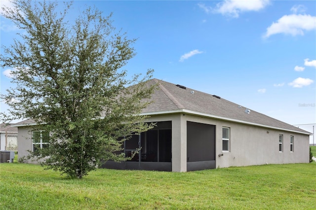 rear view of house featuring cooling unit, a yard, and a sunroom