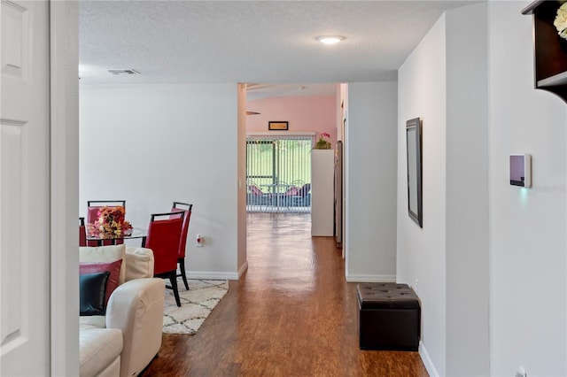 hallway with hardwood / wood-style floors and a textured ceiling