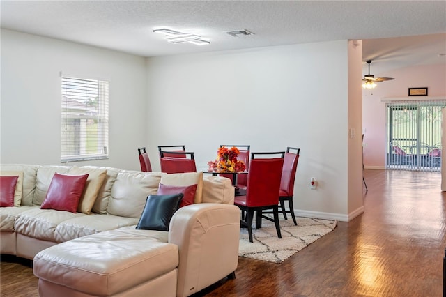 living room featuring dark hardwood / wood-style flooring, a textured ceiling, and ceiling fan