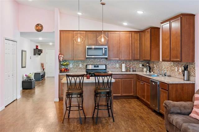 kitchen featuring lofted ceiling, decorative light fixtures, stainless steel appliances, a breakfast bar area, and decorative backsplash