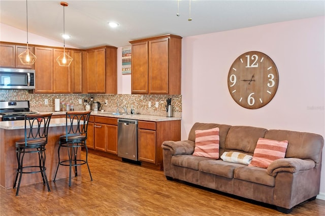 kitchen with stainless steel appliances, tasteful backsplash, decorative light fixtures, and a kitchen breakfast bar