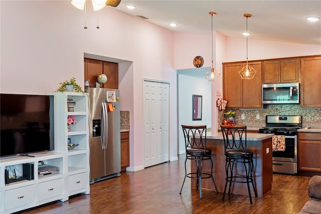 kitchen featuring a center island, dark hardwood / wood-style flooring, hanging light fixtures, appliances with stainless steel finishes, and a kitchen bar